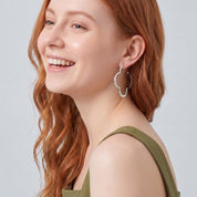 Silver clover hoop earring in a laughing portrait