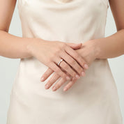 Rose gold shell ring worn with hands clasped at the waist