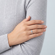 Hand on a grey knit sleeve wearing a light blue crystal ring