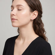 Silver faceted huggie earring worn with chin lifted