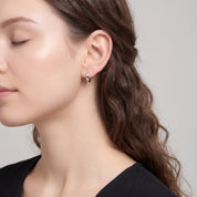 Silver faceted huggie earring in side profile with a black dress