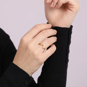 Gold wave ring worn while holding a black sleeve cuff