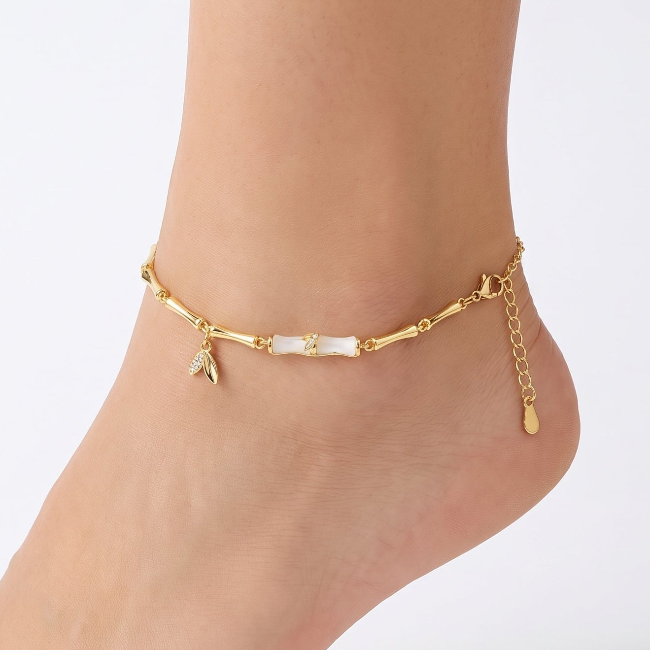 Gold bamboo anklet with crystal leaf charm worn on the ankle