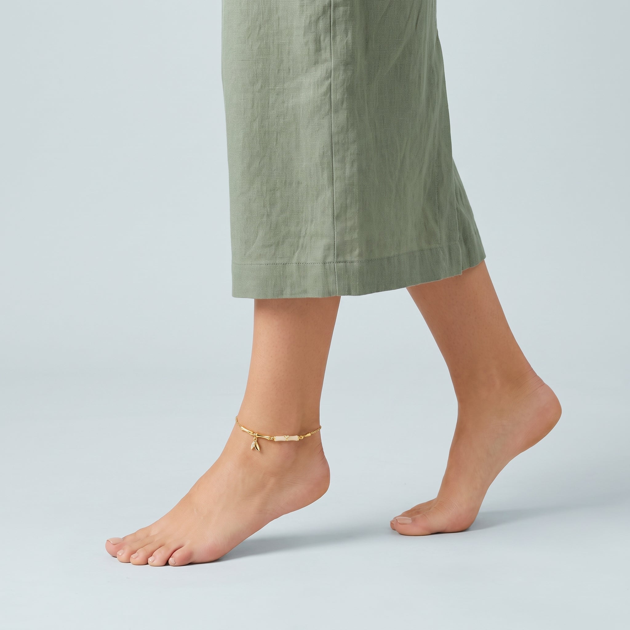 Gold bamboo anklet worn mid-step with a sage linen skirt