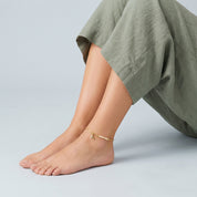 Gold bamboo anklet worn seated, side view