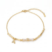 Gold bamboo anklet with white segment laid flat on white