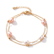 Gold two-chain bracelet with pink and white freshwater pearls on white