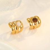 Pair of gold earrings with gemstones on a light background