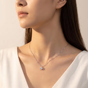 Silver solitaire necklace worn in soft side light