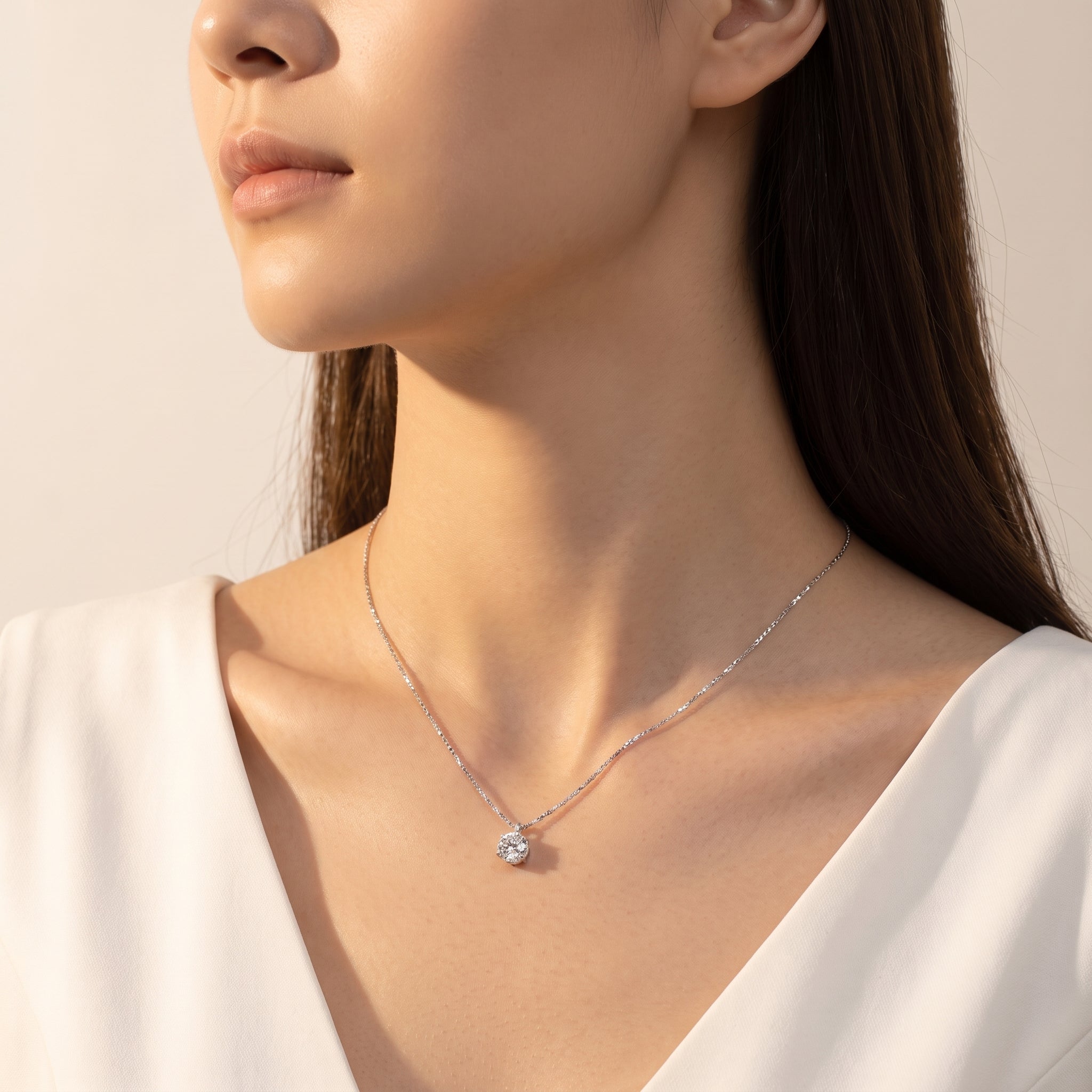 Silver solitaire necklace worn in soft side light