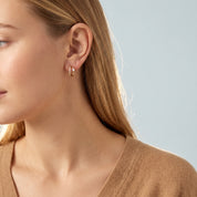 Gold double hoop earring worn with a camel V-neck sweater