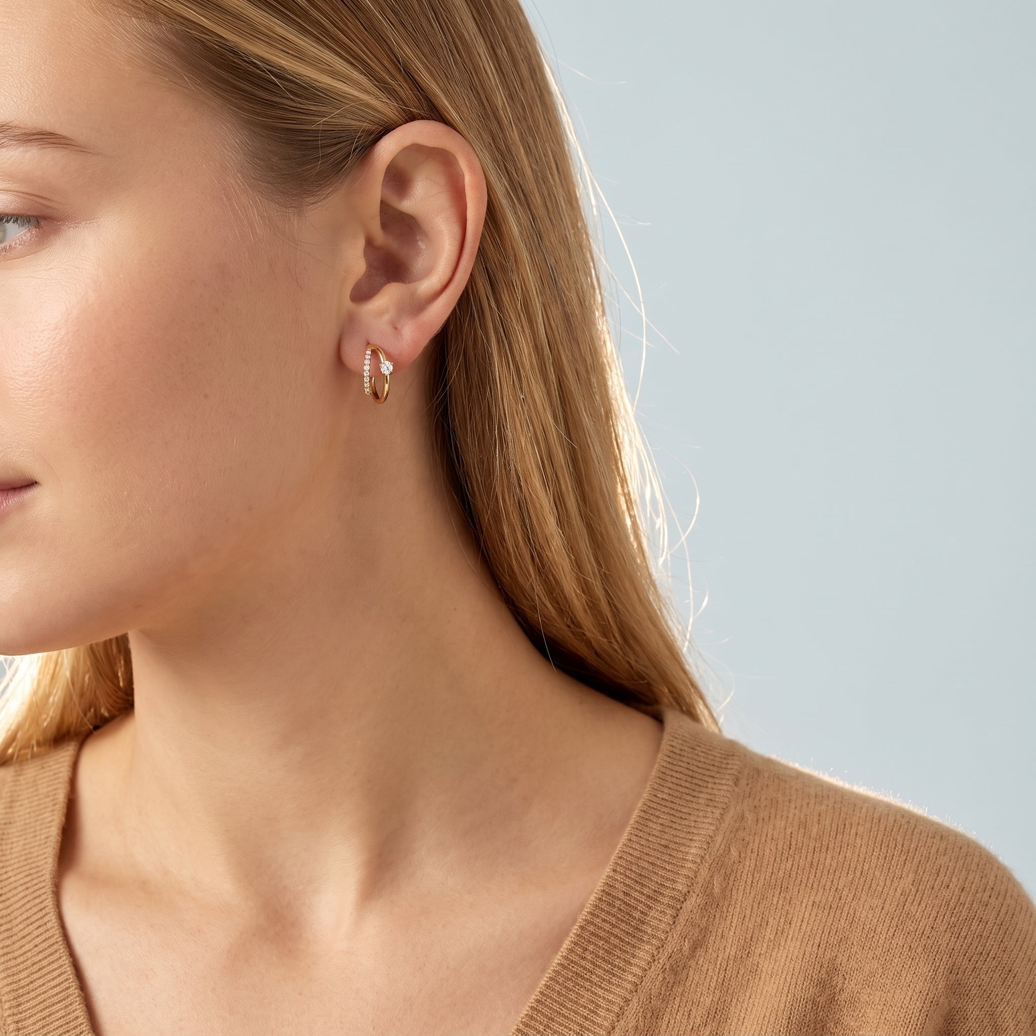 Gold double hoop earring worn with a camel V-neck sweater