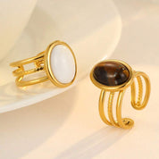 Two gold rings with gemstones on a light background