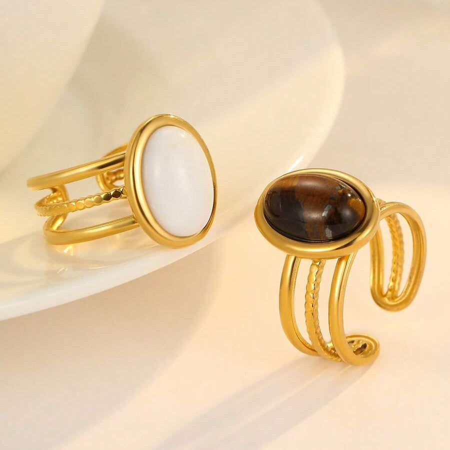 Two gold rings with gemstones on a light background