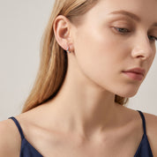 Silver teardrop hoop earring in a downcast portrait