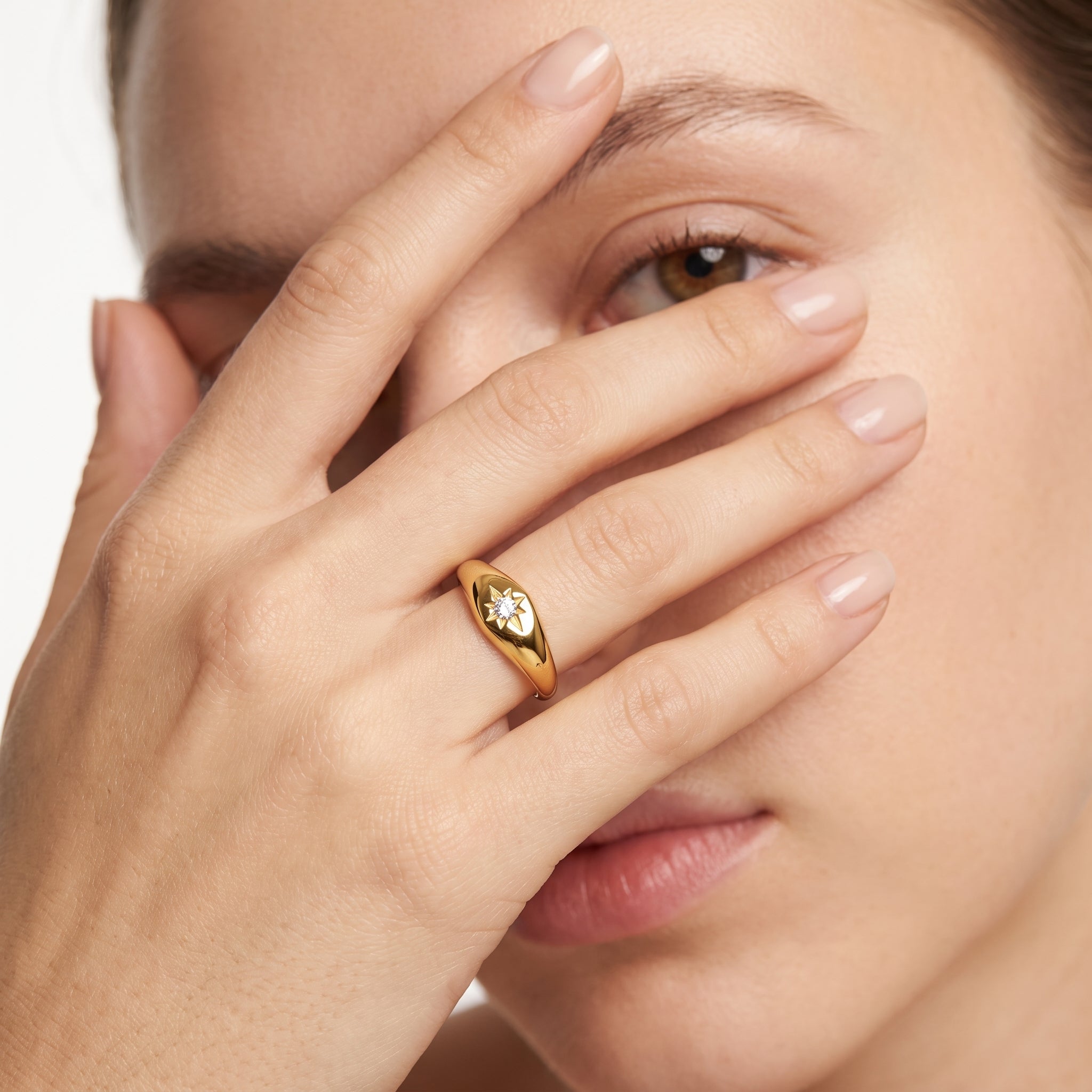 Gold star signet ring worn with the hand across the face
