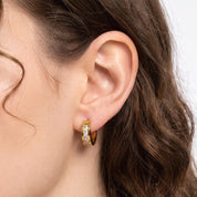 Ear wearing Navalli gold crystal huggie earring Maelle with channel-set stones