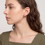 Side profile of woman in olive dress wearing Maelle channel-set huggie earring