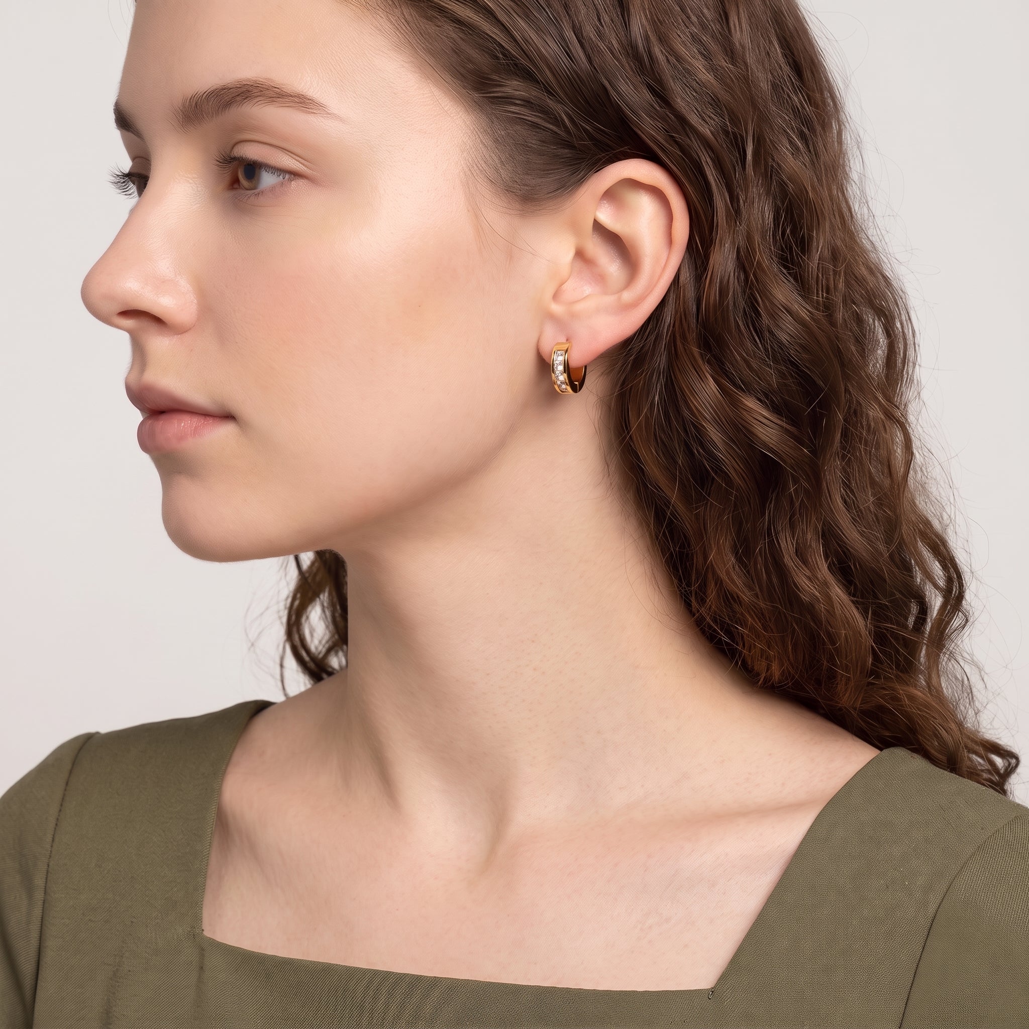 Side profile of woman in olive dress wearing Maelle channel-set huggie earring