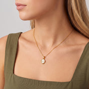 Maelle gold initial necklace worn at the collarbone with an olive dress