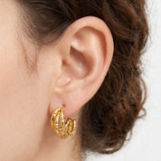 Gold textured triple hoop earrings worn on the earlobe