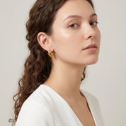 Gold textured triple hoop worn with a white V-neck top