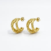 Pair of gold textured triple hoop earrings on white