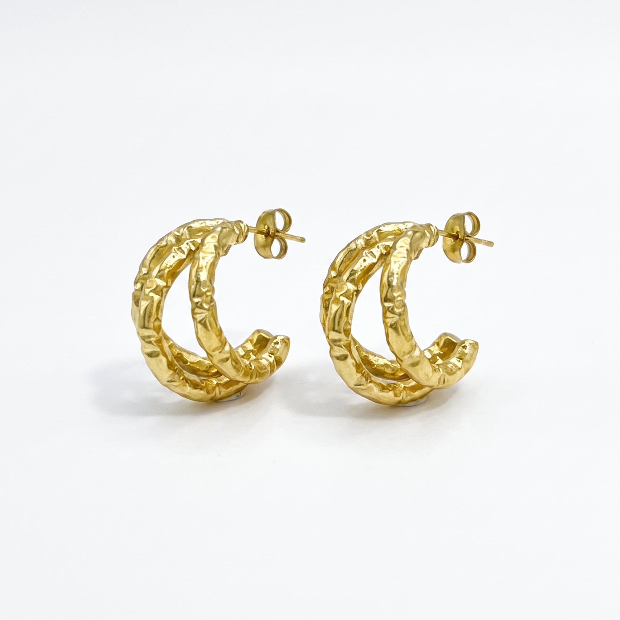 Pair of gold textured triple hoop earrings on white