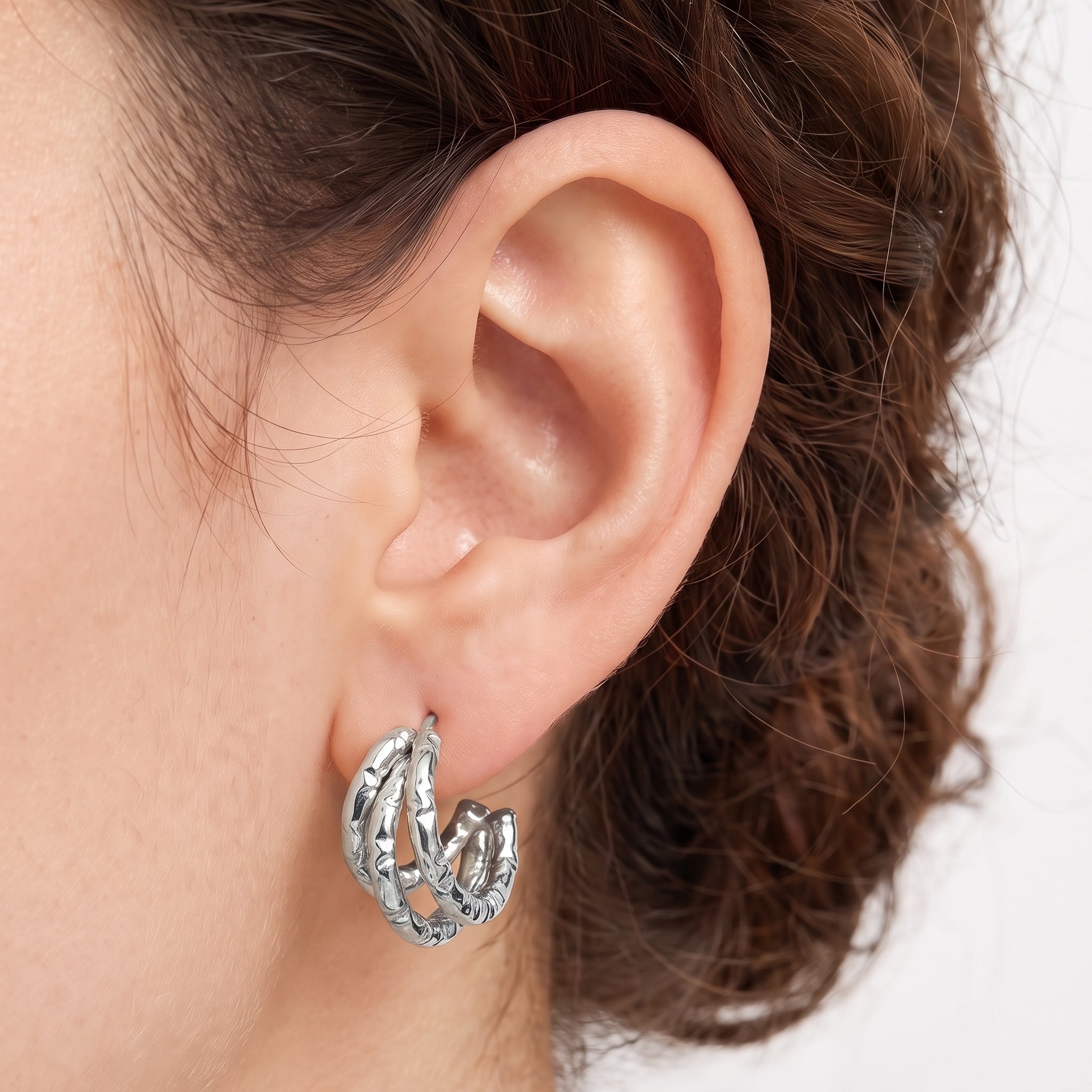 Silver textured triple hoop earrings worn on the earlobe