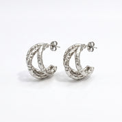 Pair of silver textured triple hoop earrings on white