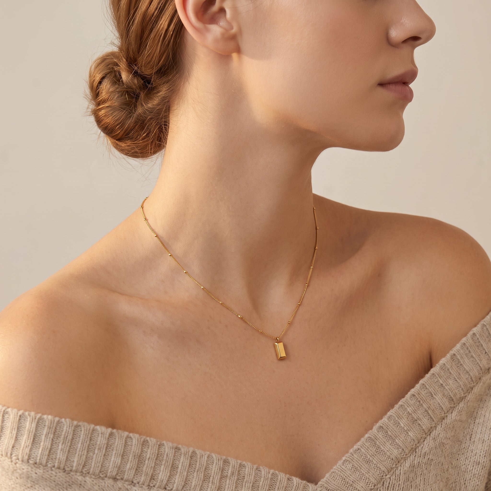 Gold bar necklace worn with an off-shoulder sweater