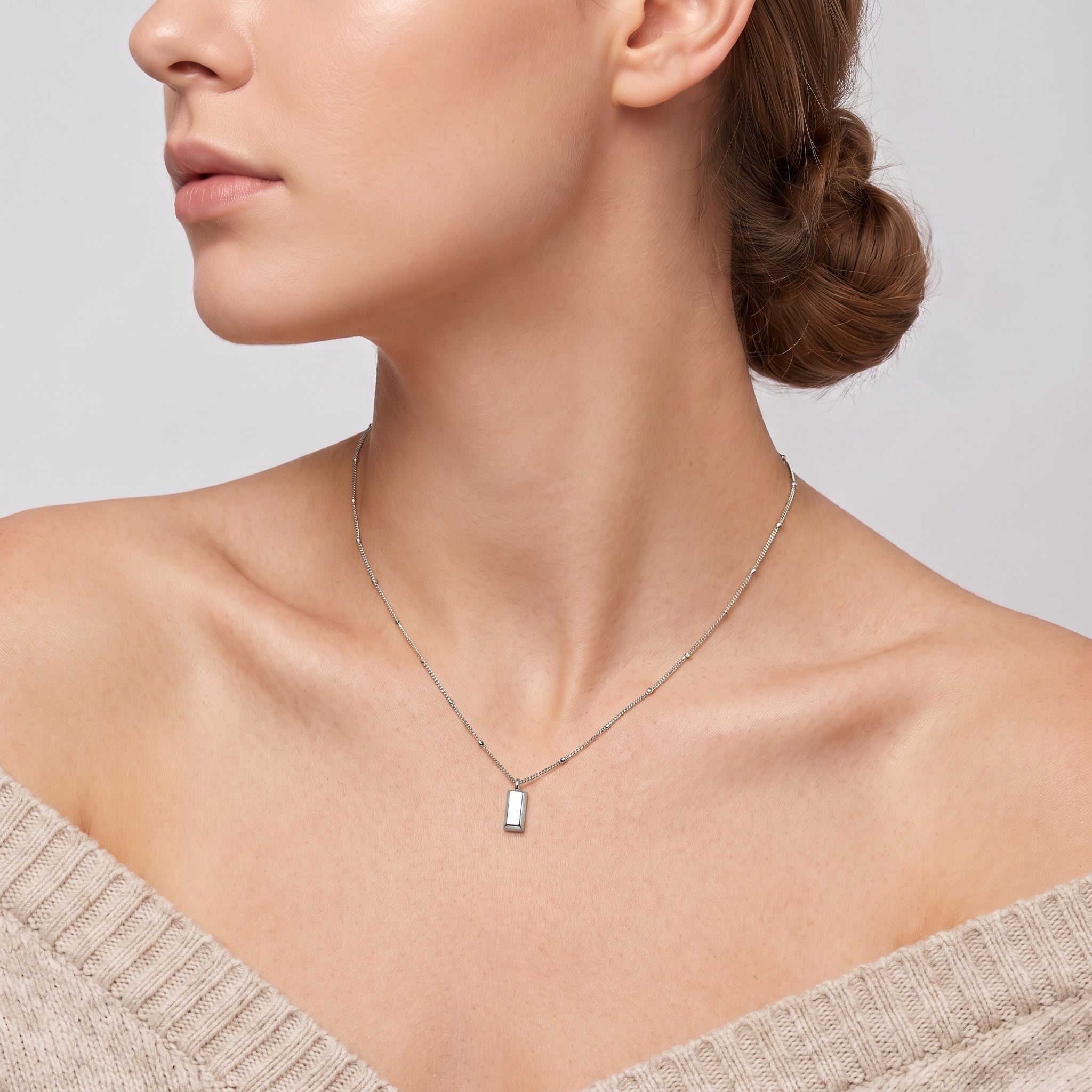 Silver bar pendant necklace on a beaded chain, worn at the neck