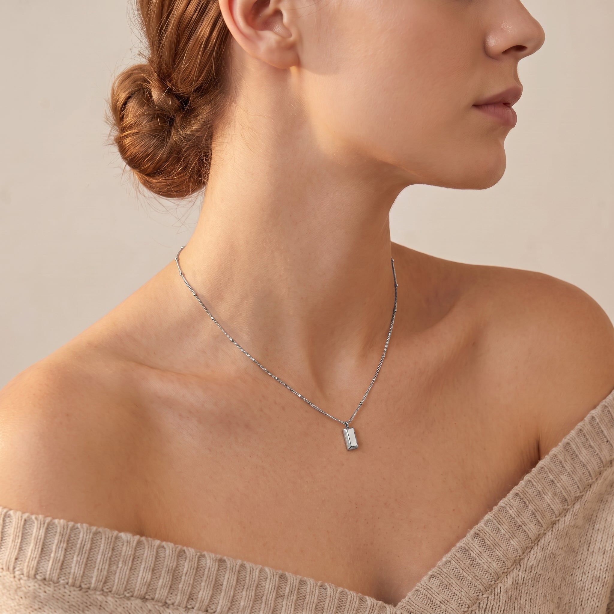 Silver bar necklace worn with an off-shoulder sweater