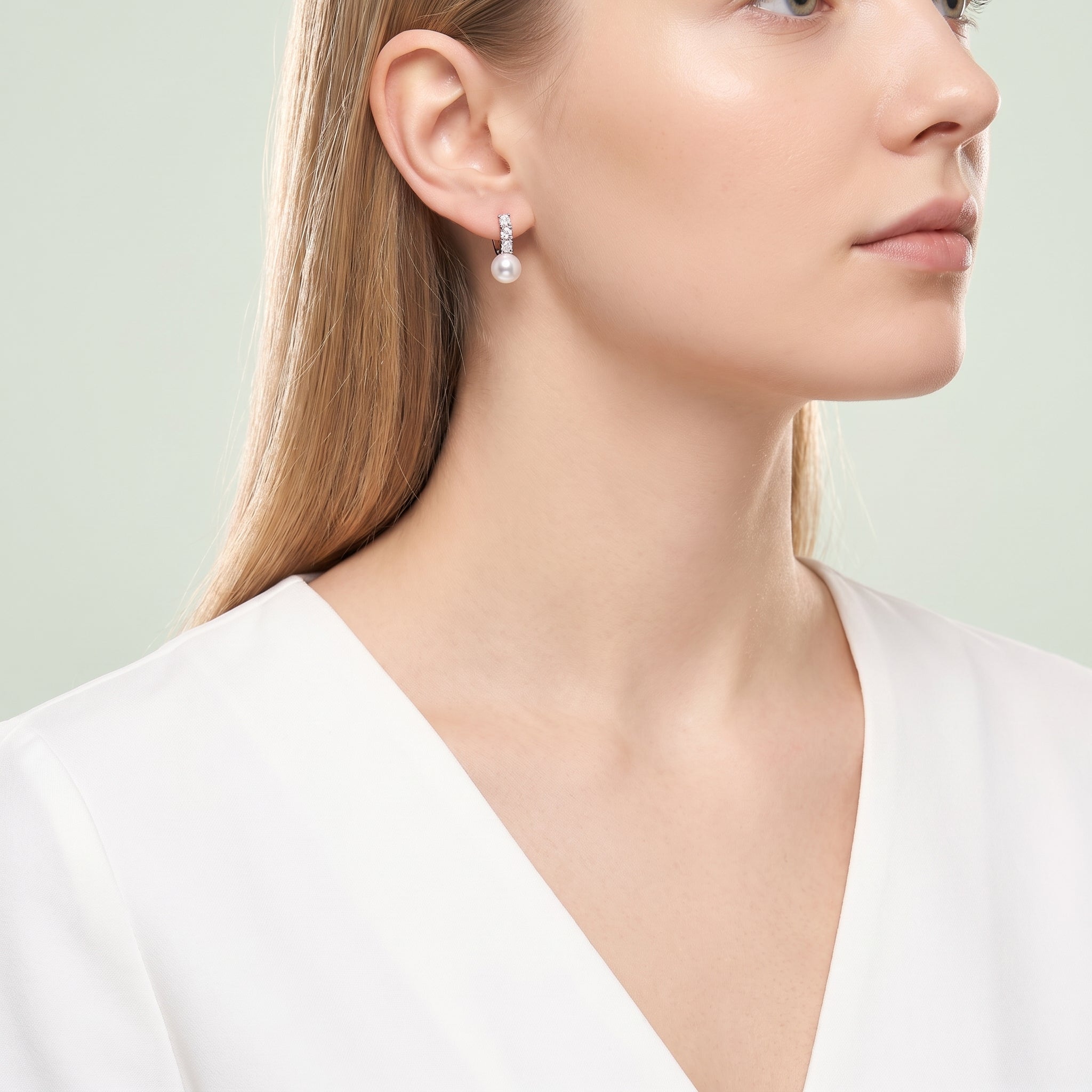 Woman in a white V-neck wearing small pearl drop huggies