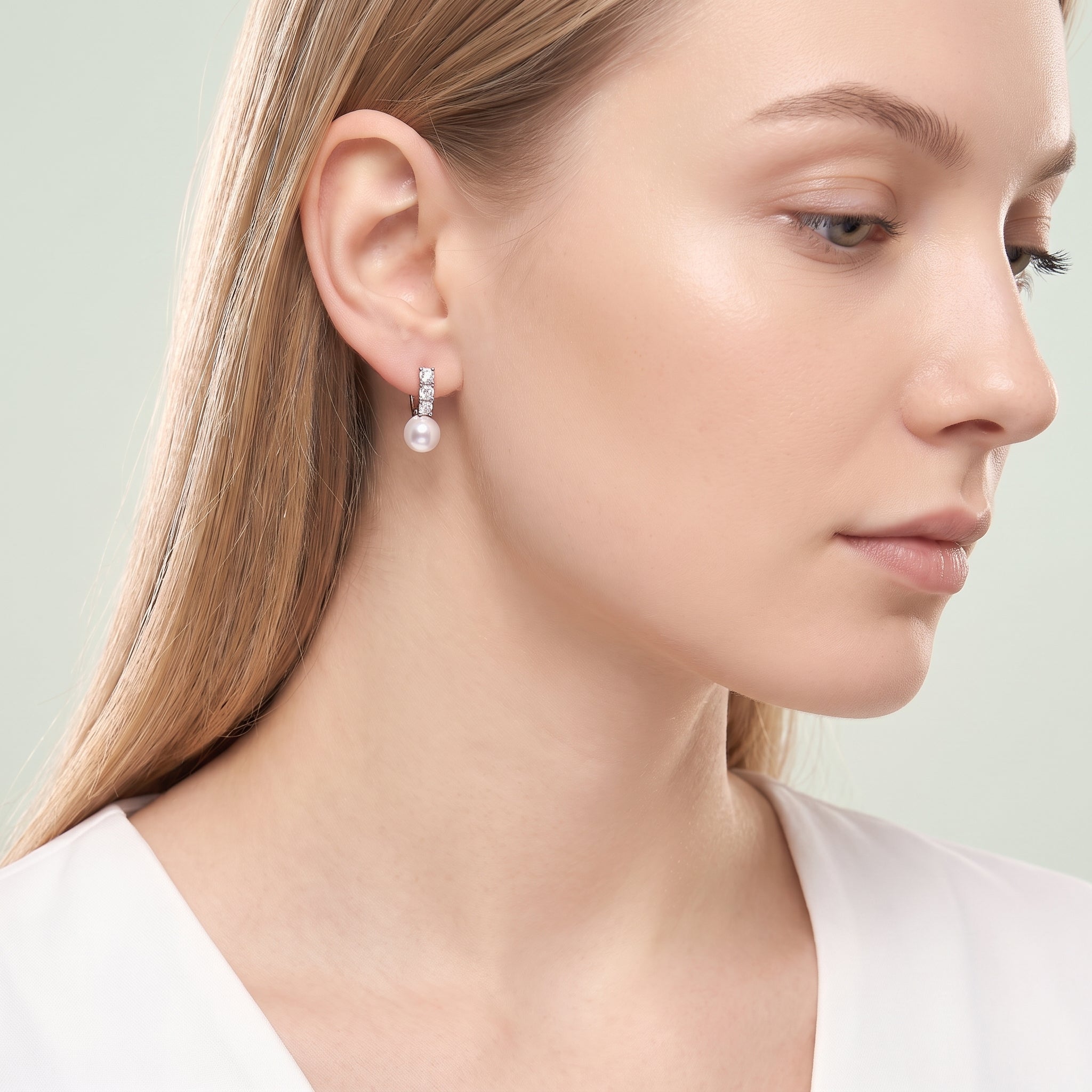 Downcast portrait with a silver pearl drop huggie earring