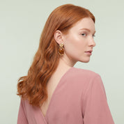 Gold amber resin drop earring seen over the shoulder