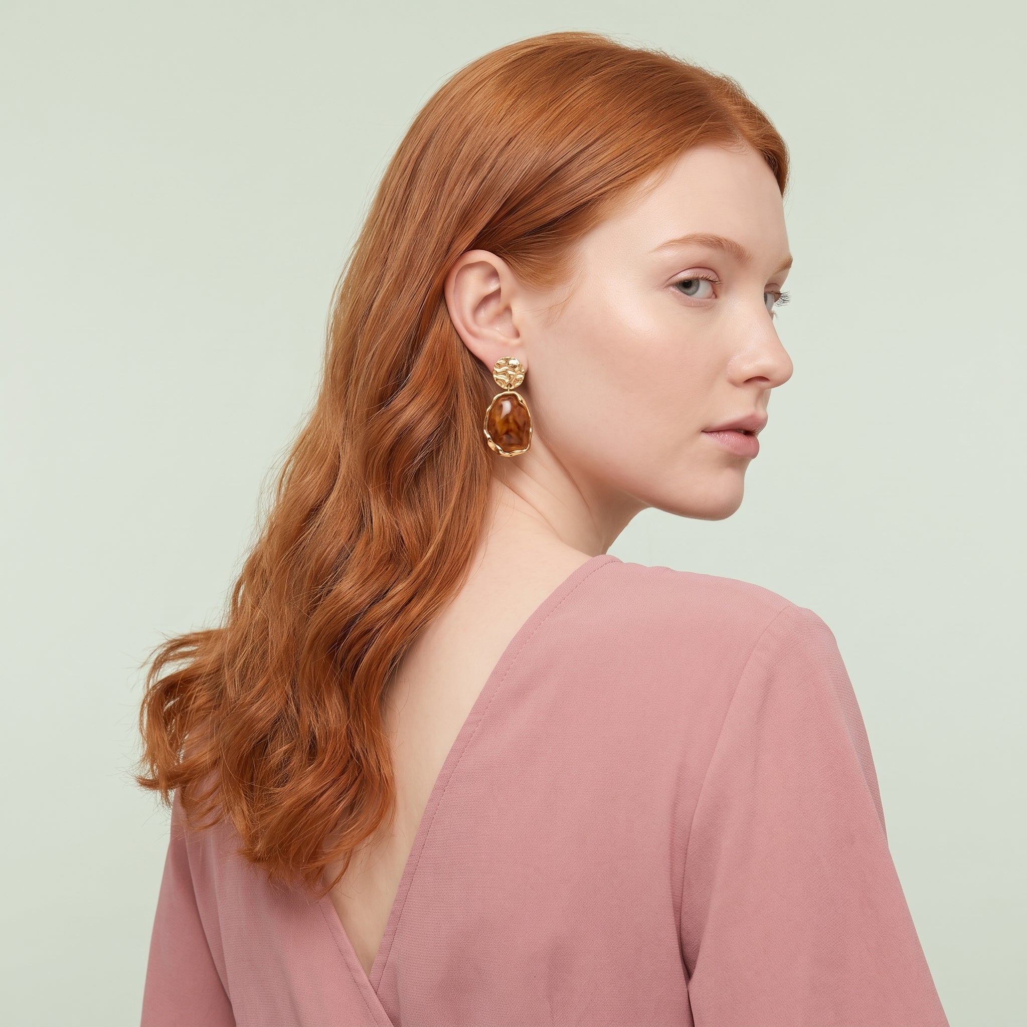 Gold amber resin drop earring seen over the shoulder