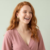 Gold amber resin drop earring worn with a dusty pink top