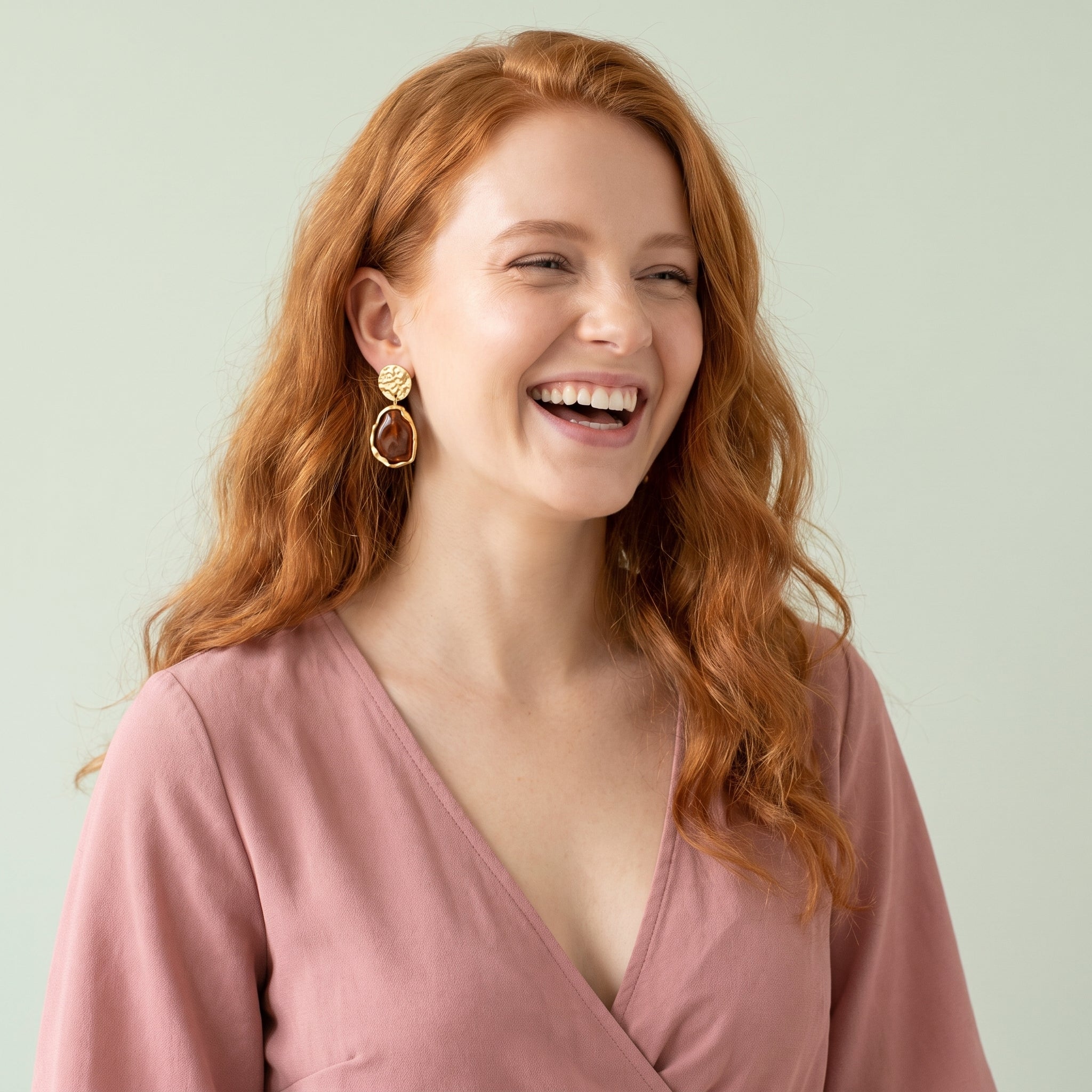Gold amber resin drop earring worn with a dusty pink top