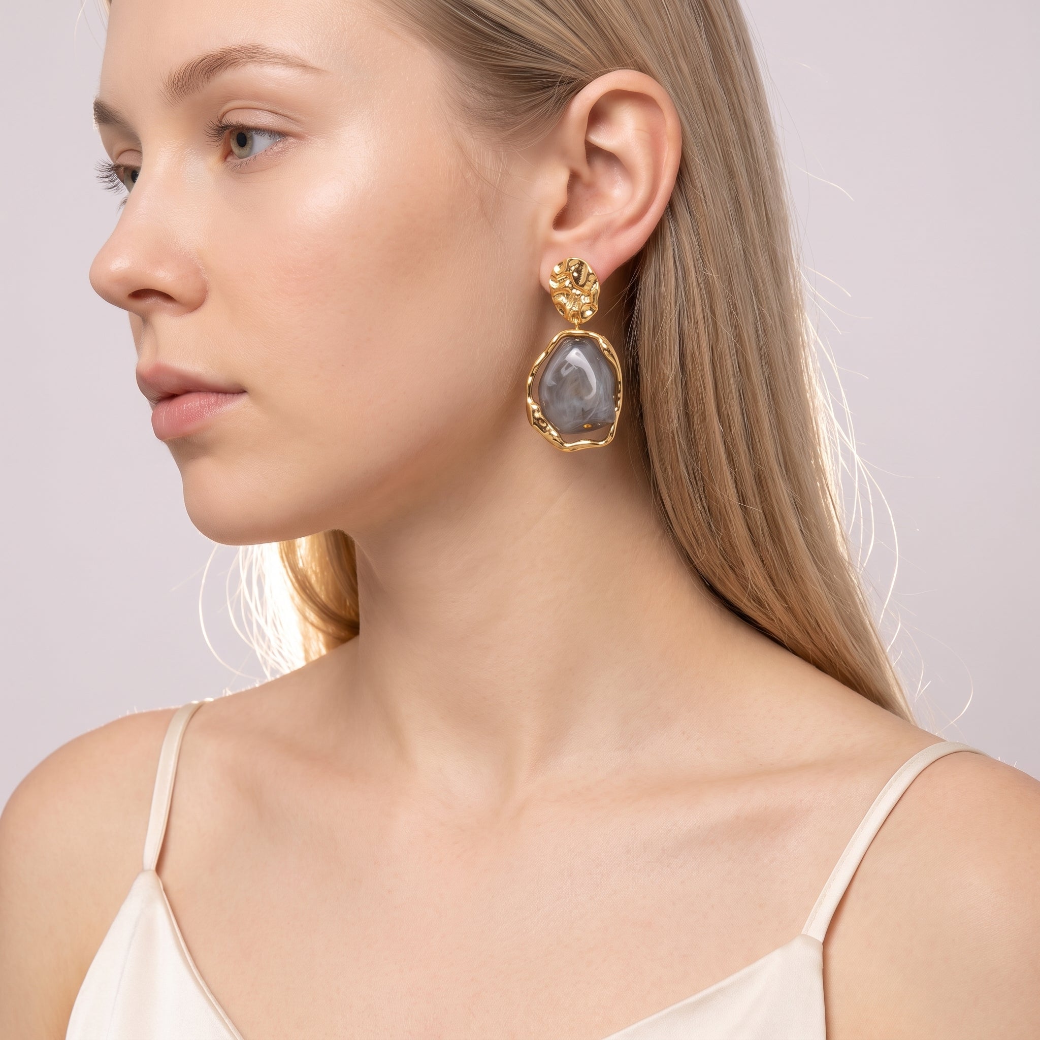 Gold grey resin drop earring worn with a cream slip dress