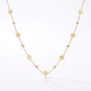 Gold star station necklace hanging in a V on a white background