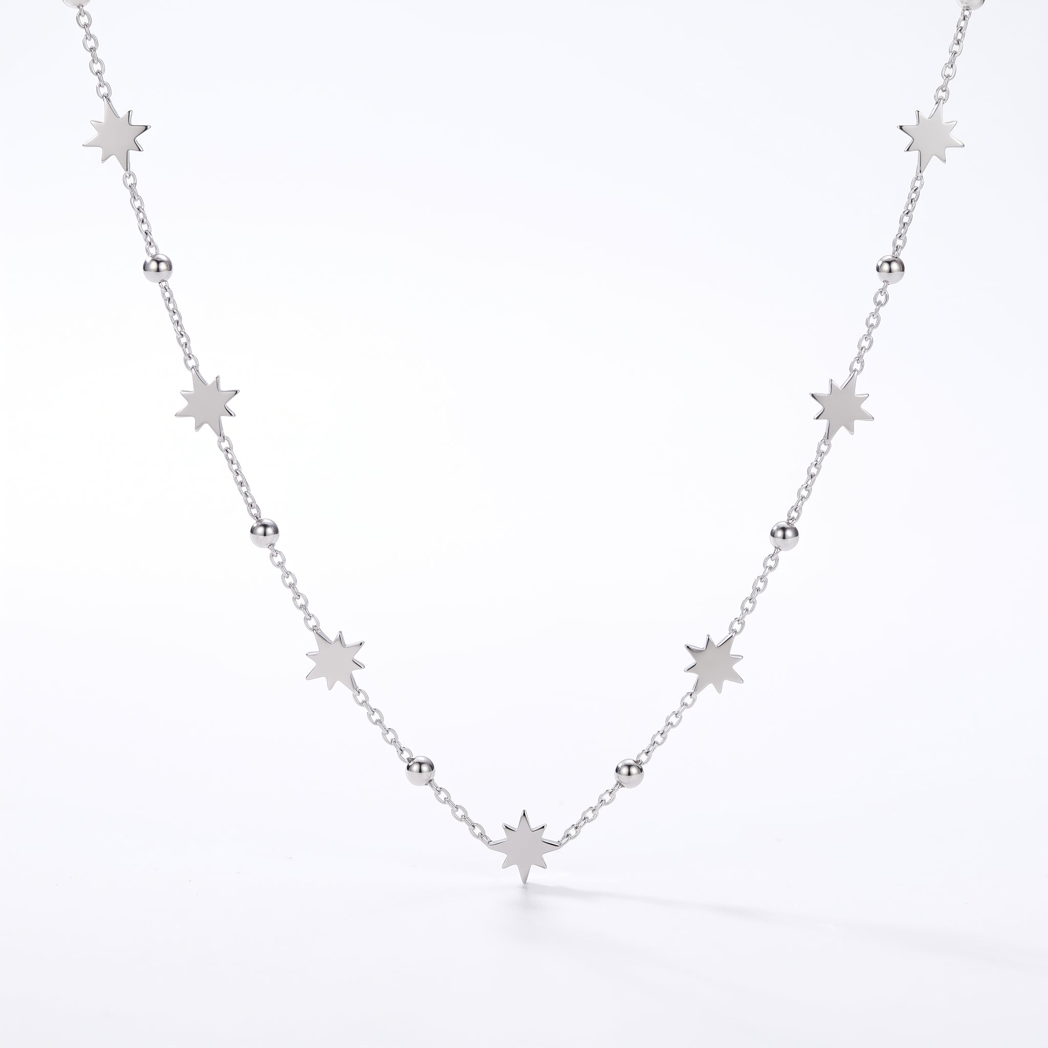 Silver chain with starburst charms and polished beads on white