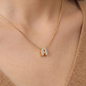 Close-up of the gold bubble letter necklace's pavé A on skin