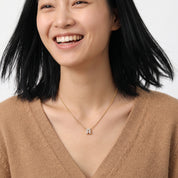 Gold bubble letter necklace worn with a camel V-neck sweater