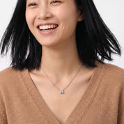 Silver bubble letter necklace worn with a camel V-neck sweater