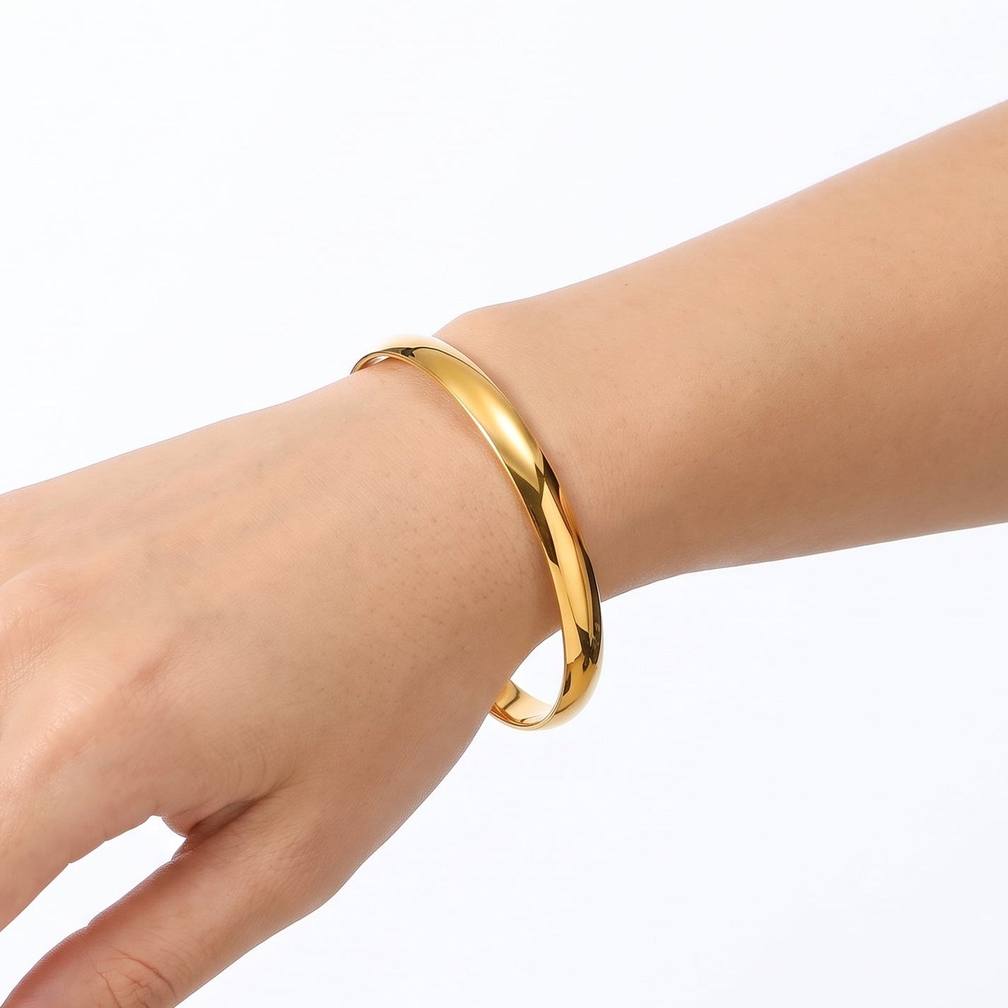 Gold smooth bangle bracelet worn loosely on the wrist