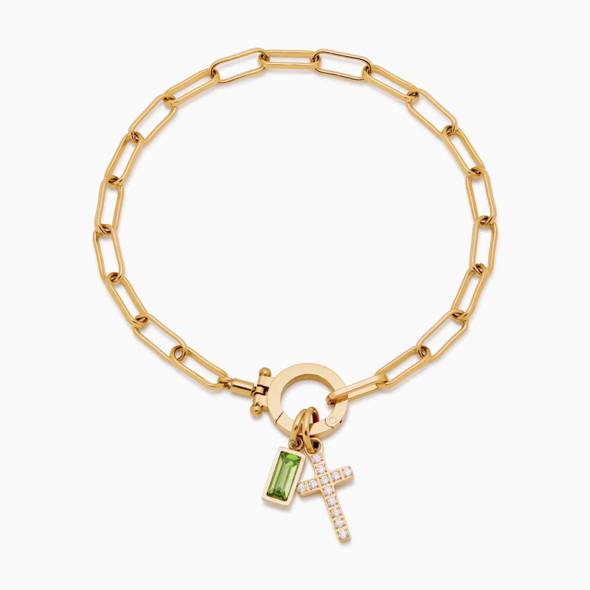 Gold bracelet with a green gemstone and cross charm on a white background