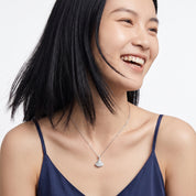 Smiling woman wearing a small silver pavé pendant necklace