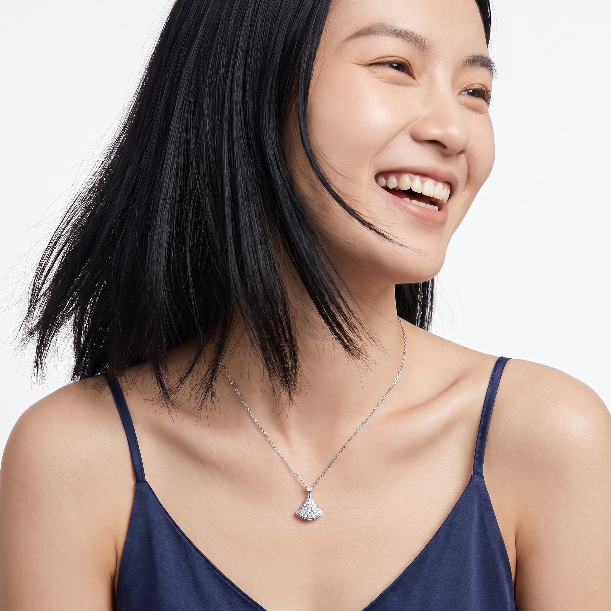 Smiling woman wearing a small silver pavé pendant necklace