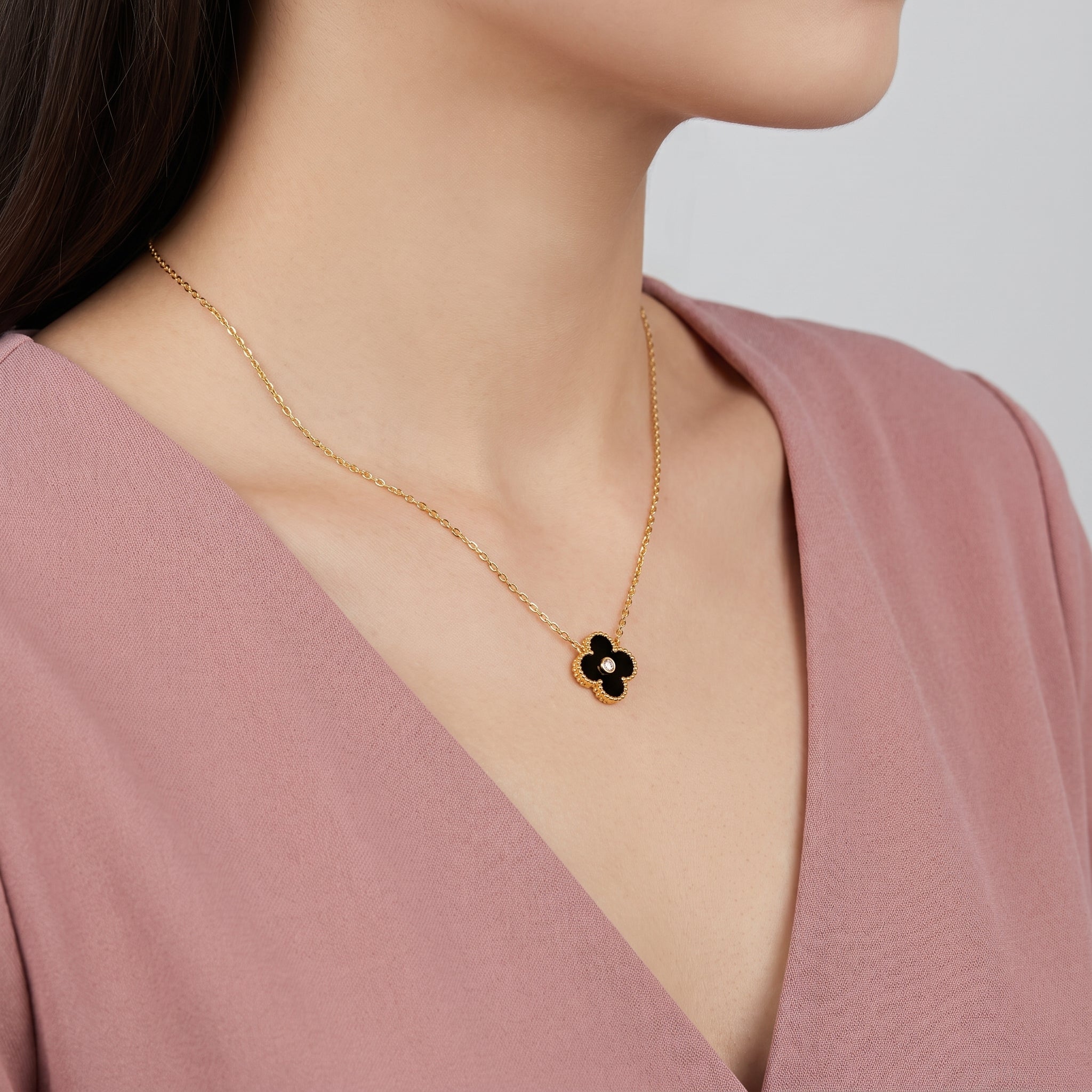 Gold black clover necklace with crystal center worn at the collarbone
